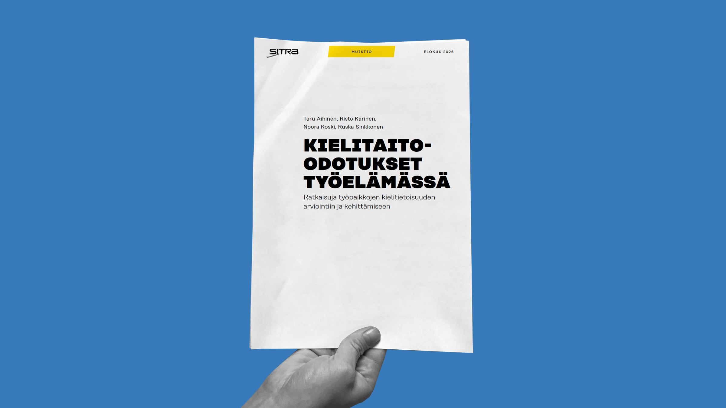 Kädessä on suomenkielinen raportti, jonka kansi on valkoinen ja tausta sininen. Otsikko ”Kielitaito-odotukset työelämässä” on keskitetty lihavoidulla mustalla tekstillä.